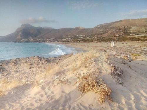 a sandy beach with the ocean and mountains in the background at Manolo s olive farm, apartment with seaview in Chania Town