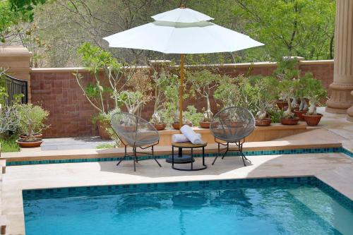 a patio with two chairs and an umbrella next to a pool at The Almond Tree in Jodhpur