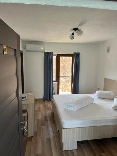 a bedroom with a large white bed and a window at Vila Angi in Mangalia