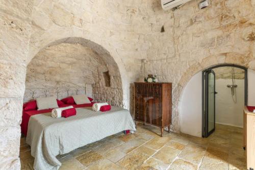 um quarto com uma cama numa parede de pedra em Villa Trullo Lofino by Villa Plus em Carovigno