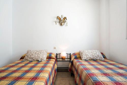 a bedroom with two beds and a light on the wall at Villa Acuario - especial familias in Barbate