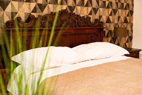 a bed with a wooden headboard and white pillows at Original Sicily in Santa Venerina