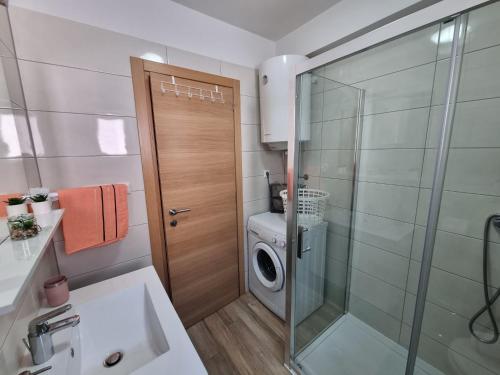 uma casa de banho com uma máquina de lavar roupa e uma porta de vidro em Apartman Marija em Biograd na Moru
