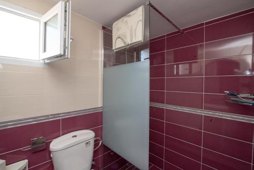 a bathroom with a toilet and red tiles at Grcka Reni Greece Beach Penthaus 3 in Nea Kalikratia