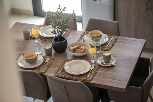 a wooden table with plates and bowls of food on it at Delight Luxury Villa - Contemporary Elegance & Tranquility, by ZanteWize in Zakynthos Town