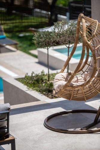 a wicker chair sitting on a patio next to a pool at Delight Luxury Villa - Contemporary Elegance & Tranquility, by ZanteWize in Zakynthos Town