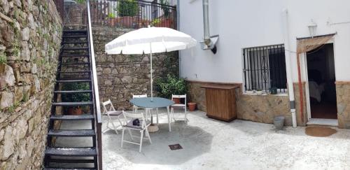 a patio with a table and an umbrella and a staircase at La Casa Grande in Benaocaz