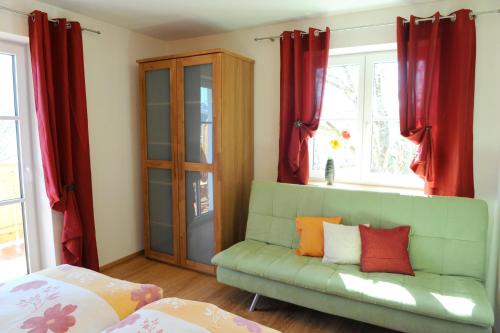 a green couch in a room with red curtains at Appartements - Haus Sieberer in Brixen im Thale