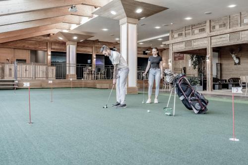 a man and a woman playing golf in a mall at SKI - GOLF - WELLNESS Hotel Riml in Hochgurgl