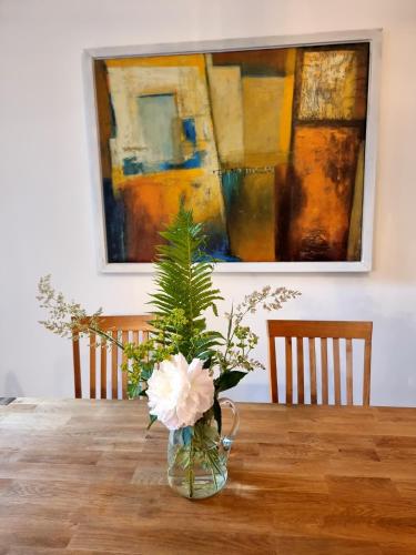 a vase with flowers on a table with a painting at Hostel Lollis Homestay Dresden in Dresden