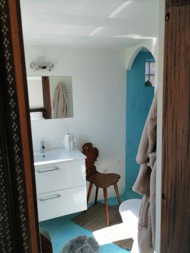 une salle de bain avec un lavabo blanc et une chaise dans l'établissement Menton Mignon 2p bucolique vue mer campagne, à Menton