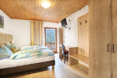 a bedroom with a bed and a desk and a window at Veltierhof in Funes