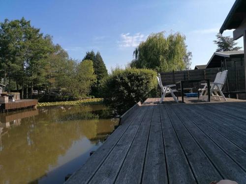 a wooden deck with two chairs sitting on it at Le canard: rustig genieten aan het water in Geel