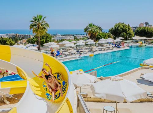 a pool at a resort with two people on a slide at Louis St. Elias Resort & Waterpark in Protaras