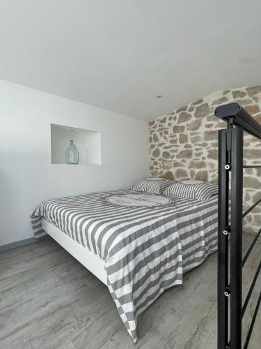 une chambre avec un lit avec un mur en pierre dans l'établissement Sainte Victoire le Cabanon, à Puyloubier