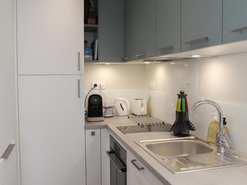 une cuisine avec des armoires blanches et un évier dans l'établissement La Chaume appartement coquet 4 personnes 3* wifi - FR-1-485-121, à Les Sables-dʼOlonne