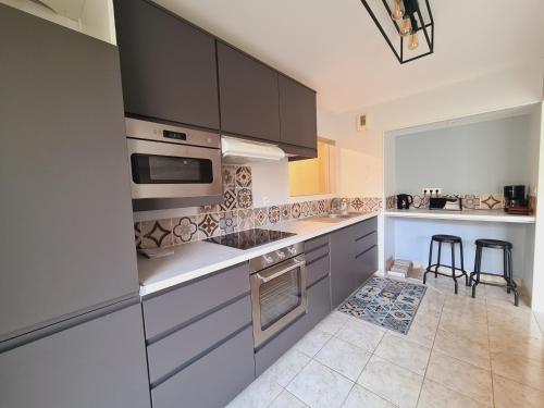 La cuisine est équipée de placards gris et d'un four avec plaques de cuisson. dans l'établissement Appartement spacieux, centre ville, 2 chambres, parking, proche toutes commodités - FR-1-485-122, à Les Sables-dʼOlonne