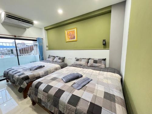 two beds in a room with green walls at Variety winner hostel in Hat Yai