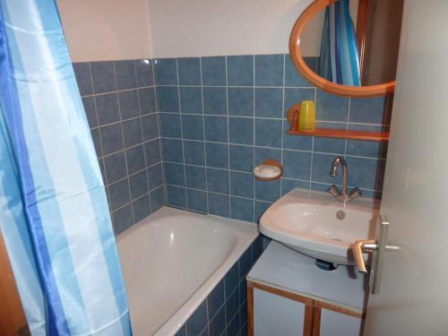 La salle de bains est pourvue de carrelage bleu, d'un lavabo et d'une baignoire. dans l'établissement Appartement Duplex 2 Pièces au Pied des Pistes - FR-1-573-82, à Saint-Jean-dʼAulps