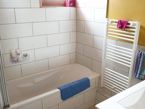 La salle de bains est pourvue d'une baignoire blanche et d'une serviette bleue. dans l'établissement Beau duplex 3 pièces au pied des pistes avec TV, DVD, balcon, et parking à Saint-Jean-d'Aulps - FR-1-573-72, à Saint-Jean-dʼAulps
