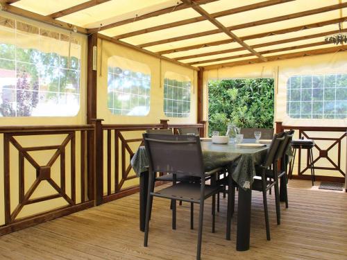 une salle à manger avec une table, des chaises et des fenêtres dans l'établissement Charmante maison bois avec piscine chauffée, climatisation et jardin - 4 couchages, St-Pierre-d'Oléron - FR-1-246A-132, à Saint-Pierre-dʼOléron