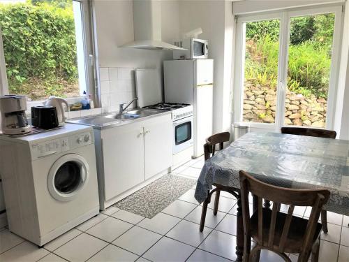une cuisine avec une machine à laver et une table avec des chaises dans l'établissement Maison spacieuse avec jardin clos à 550m de la plage à Perros-Guirec - FR-1-368-349, à Perros-Guirec
