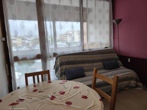 - une chambre avec une table, un lit et une fenêtre dans l'établissement T1 proche Parc Charles de Gaulle, 1er étage avec ascenseur, loggia, tout équipé, idéale pour 2 personnes - FR-1-571-55, à Balaruc-les-Bains