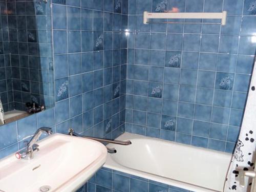 W wyłożonej niebieskimi kafelkami łazience znajduje się wanna i umywalka. w obiekcie Appartement Saint-Jean-d'Aulps, 1 pièce, 4 personnes - FR-1-573-86 w mieście Saint-Jean-dʼAulps