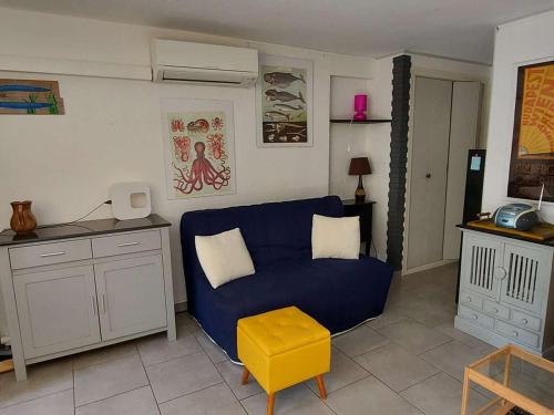 - un salon avec un canapé bleu et un tabouret jaune dans l'établissement Appartement climatisé 3 pièces, 6 pers, terrasse, BBQ, parking privé, à 100 m de la plage - FR-1-423-253, au Grau-dʼAgde