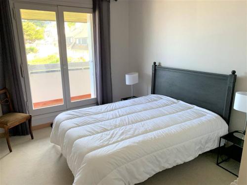 une chambre avec un grand lit et une grande fenêtre dans l'établissement Appartement avec terrasse, parking, plage de Trestraou à Perros-Guirec - FR-1-368-350, à Perros-Guirec