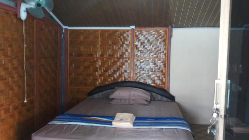 a small bed in a room with a wooden wall at Diara bungalow in Iboih