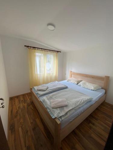 un grande letto in una camera da letto con pavimento in legno di Apartmani LALA Canj a Čanj