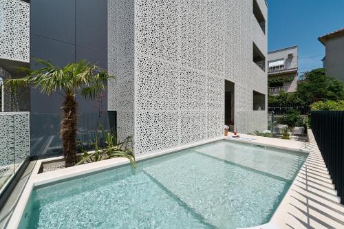 a swimming pool in front of a building with a palm tree at Luxury Apartments Villa Mala Split in Split