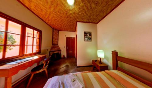 a bedroom with a bed and a desk and a fireplace at Pousada Albuquerque in Teresópolis