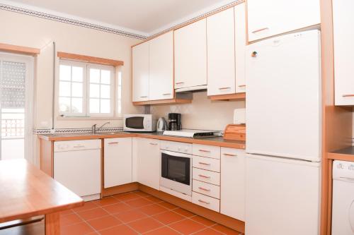 a kitchen with white cabinets and a red tile floor at 19 Aldeia Viriato in Casal da Lagoa Seca