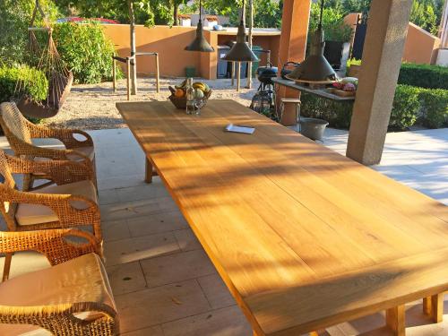 a long wooden table in a patio with chairs at Le Jardin des Copains in Canet