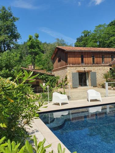 une piscine avec deux chaises blanches et un bâtiment dans l'établissement Gîtes de Charme 