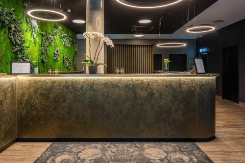 a lobby with a gold counter and a green wall at Abasto Hotel Dachau in Dachau