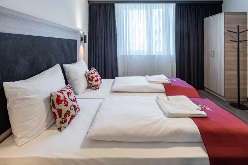 two beds in a hotel room with white sheets and pillows at Abasto Hotel Dachau in Dachau