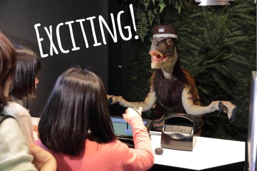 un grupo de personas sentadas en un escritorio con una estatua de dinosaurio en Henn na Hotel Maihama Tokyo Bay, en Urayasu