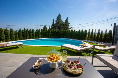 Villa Lumani ** Luxury residence near Split ** في Kučine: طاولة عليها طعام بجوار حمام سباحة