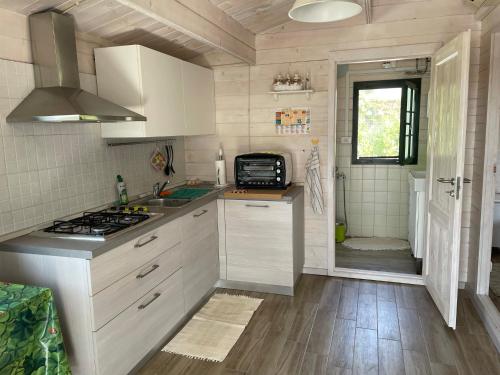 a kitchen with white cabinets and a sink and a stove at Casetta Arùci Marzamemi Holidays in Marzamemi