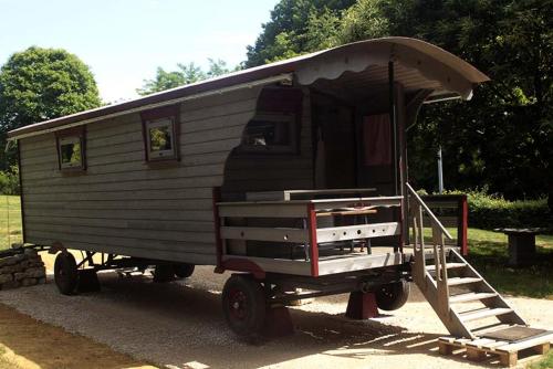 a mobile home with a roof on a trailer at Belle Roulotte unique en pleine campagne Au Jardin de la Vouivre in Saint-Vincent-en-Bresse