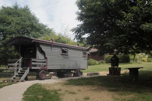 a trailer with a horse standing next to a house at Belle Roulotte unique en pleine campagne Au Jardin de la Vouivre in Saint-Vincent-en-Bresse