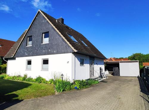 Biały dom z czarnym dachem i podjazdem w obiekcie Ferienhaus Blue Pearl w mieście Scharbeutz