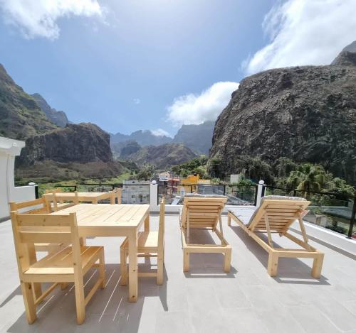 een houten tafel en stoelen op een balkon met uitzicht op de bergen bij Kasa d'Vizin in Paul