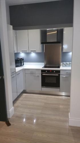 uma cozinha com armários brancos e um forno com placa de fogão em CityGo Apartments Queens Wellington em Belfast