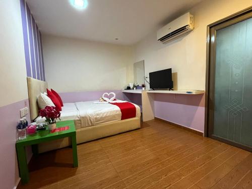 a bedroom with a bed and a desk and a television at City Boutique Hotel - Bangi in Bangi