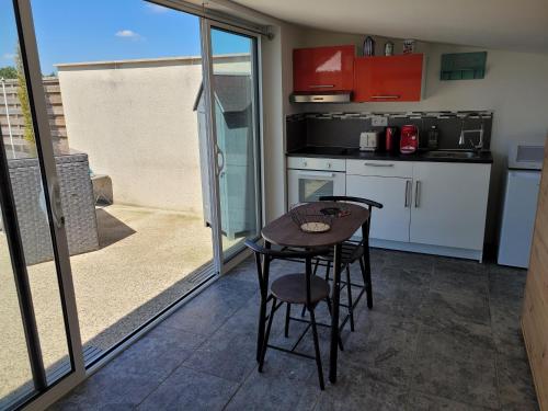 eine kleine Küche mit einem Tisch und Stühlen in der Unterkunft La pool house in Saint-Aubin-du-Plain