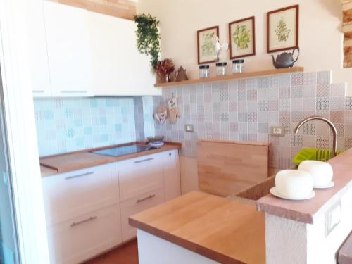 a kitchen with white cabinets and blue tiles at La Solina in Bibbona